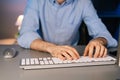 Close-up of hands of unrecognizable man using wireless keyboard and computer mouse at dark room. Royalty Free Stock Photo