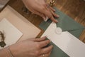 Top view of hands of unrecognizable woman holding grey and white greeting invitation envelopes with white wax seal.