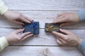 Top view of the hands of a woman and a man exchanging gifts on a wooden background. Close-up of the surprise for the vacation conc Royalty Free Stock Photo