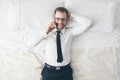 Top view. Handsome businessman with glasses on bed calling from his phone Royalty Free Stock Photo