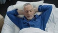 Top view of happy aged male lying in his bed and smiling, healthy sleep, morning Royalty Free Stock Photo