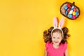 Top view on a happy baby in the ears of a bunny and a basket with Easter colored eggs. Royalty Free Stock Photo