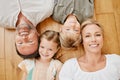 Top view of happy caucasian family lying together on the wooden floor at home. Portrait of a mature couple bonding with Royalty Free Stock Photo