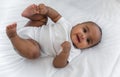 Top view of Happy cute little African newborn baby lying down smiling and looking at camera on white bed in bedroom at home Royalty Free Stock Photo