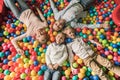 top view of happy family with two kids smiling at camera while lying in pool with colorful balls Royalty Free Stock Photo