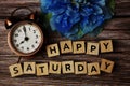 Happy Saturday alphabet letter with alarm clock on wooden background Royalty Free Stock Photo