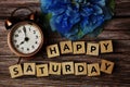 Happy Saturday alphabet letter with alarm clock on wooden background