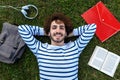 Top view of happy, smiling young caucasian man relaxing lying down on grass looking at camera. Royalty Free Stock Photo
