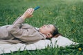Top view of a happy woman with white dress lying on the grass texting on a smart phone Royalty Free Stock Photo
