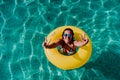 Top view of happy young woman floating in a pool in a yellow donuts. summer and fun lifestyle Royalty Free Stock Photo