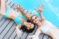 top view of happy young women in sunglasses and swimwear reaching arms and smiling at camera