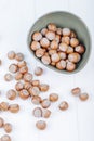 top view of hazelnuts in a bowl and scattered on white wooden background Royalty Free Stock Photo