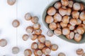 top view of hazelnuts in a bowl and scattered on white wooden background Royalty Free Stock Photo