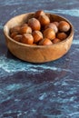 Top view of hazelnuts in wooden bowl on blue marble background Royalty Free Stock Photo