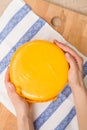 Top view on a head of fresh organic cheese in yellow vacuum package in man`s hands. Food concept Royalty Free Stock Photo