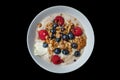Top view of healthy cereal and oatmeal breakfast with berries and nuts in a white bow