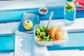 Top view healthy lunch box with wholemeal burger bun, salad with fresh vegetables, a bottle of water with mint and lemon Royalty Free Stock Photo