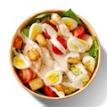 Top view of Caesar salad with lettuce, tomatoes, quail eggs, croutons, chicken and sauce in paper bowl isolated on white Royalty Free Stock Photo