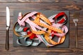 Top view of heap of colorful measuring tapes in plate on wooden background. Diet concept with copy space Royalty Free Stock Photo