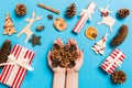 Top view of a heap of pine cones in female hands on blue backround made of festive decorations. Christmas time concept