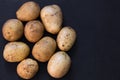 Top view of heap of unpeeled raw potato on black background