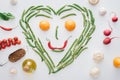 top view of heart made of fresh green peas and asparagus and smiley face from tomatoes and chili peppers Royalty Free Stock Photo