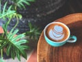 Top view of heart shape latte art coffee in green and white cup on the vintage wooden table with green leave. Royalty Free Stock Photo