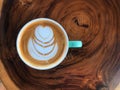 Top view of heart shape latte art coffee in green and white cup on the vintage wooden table. Royalty Free Stock Photo