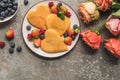 Top view of heart shaped pancakes with berries on grey concrete surface near roses Royalty Free Stock Photo