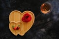 Top view of heart-shaped wooden board with a rose on it