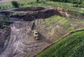 Top view heavy machine excavator bagger working in mud on construction site with green landscape surrounding