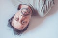 Top view high key portrait of depressed man lying in bed