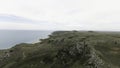 Top view of hilly coast on background of sea horizon. Shot. Coast line with hills and sparse grass with sea. Sea horizon