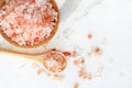 Top view of himalayan pink rock salt in wooden bowl and spoon on white marble table Royalty Free Stock Photo