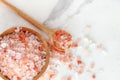 Top view of himalayan pink rock salt in wooden bowl and spoon on white marble table