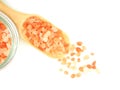 Top view, Himalayan pink salt in wooden scoop with glass bottle isolated.