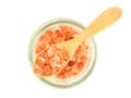 Top view, Himalayan pink salt in wooden spoon over glass bottle isolated.