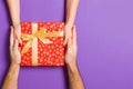 Top view of holding a gift in female and male hands on colorful background. Woman and man give and receive a present. Close up of