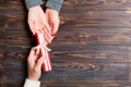 Top view of holding a gift in female and male hands on wooden background. Woman and man give and receive a present. Time for Royalty Free Stock Photo