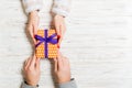 Top view of holding a gift in female and male hands on wooden background. Woman and man give and receive a present. Time for Royalty Free Stock Photo