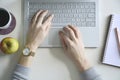 Top view home office desk with a keyboard, notebook, coffee, apple. Female hands typing on laptop keyboard Royalty Free Stock Photo