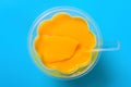 Homemade mango flavor pudding with a spoon on a blue background