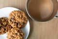 Top view of homemade oatmeal raisin cookies on a white plate and coffee atop a table illuminated with natural light Royalty Free Stock Photo