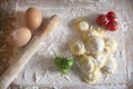 Top view of homemade Ravioli / Tortellini /dumplings with two eggs, tomatoes and peppers on floured wood