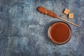 Top view on homemade sweet caramel sauce in glass bowl and brown cane sugar with sugar crystal stick Royalty Free Stock Photo