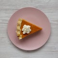 Top view, homemade Thanksgiving pumpkin pie on a pink plate on a white wooden background. Overhead, from above, flat lay. Close-up Royalty Free Stock Photo