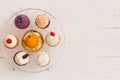 Top view on homemade vanilla, blueberyy, lemon, chocolate cupcakes on cristal plate on white retro wooden background Royalty Free Stock Photo