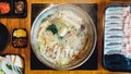 Top view of hot and boiling Shabu broth with cabbage, eryngii, enotitake, tofu and Kurobuta pork inside hot pot