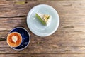 Top view of hot cappuccino coffee and  home made cake in the cafe, Heart shaped cappuccino coffee in blue cup on a wooden table Royalty Free Stock Photo