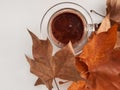 Top view of hot chocolate and autumn leaves on white table